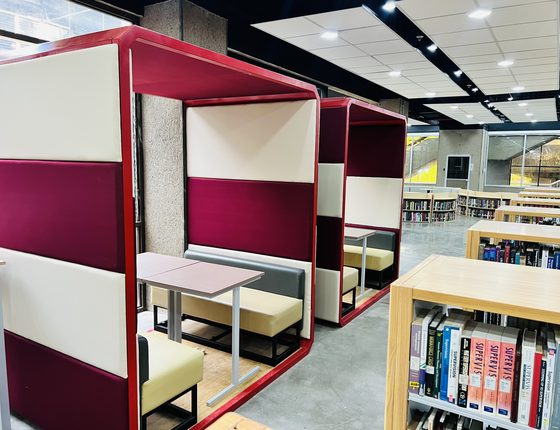 Silliman University learning commons with maroon study pods and open shelving