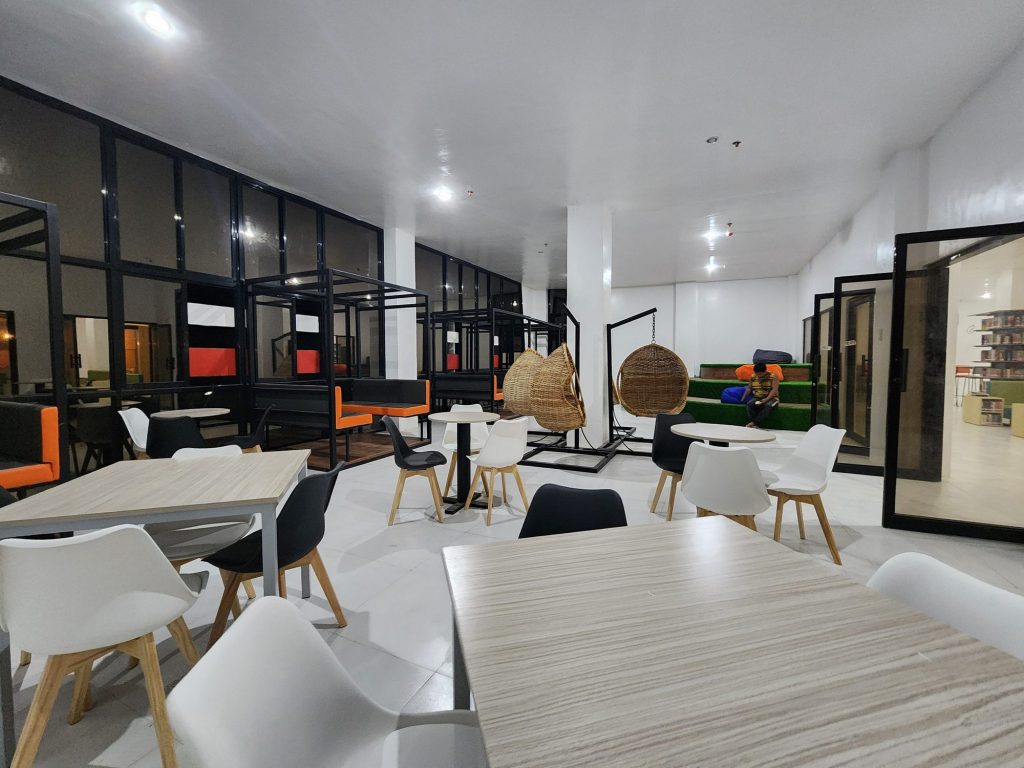 Bright open study floor with white chairs and glass-walled rooms