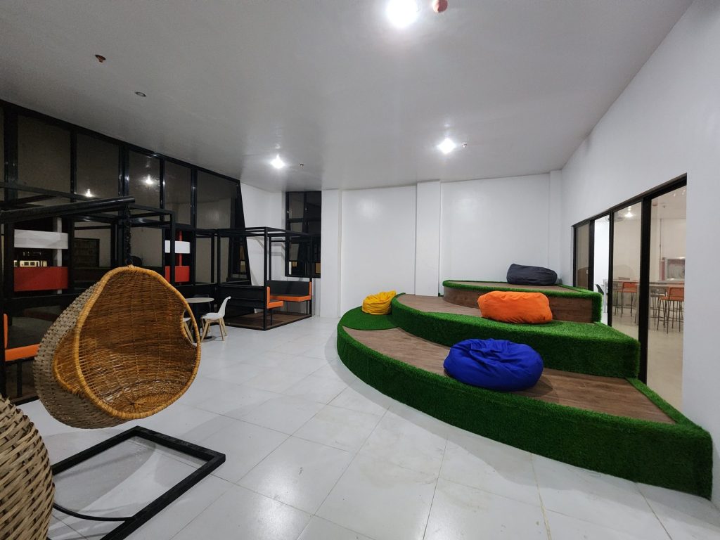 Hanging rattan pod chairs on a green astroturf mound