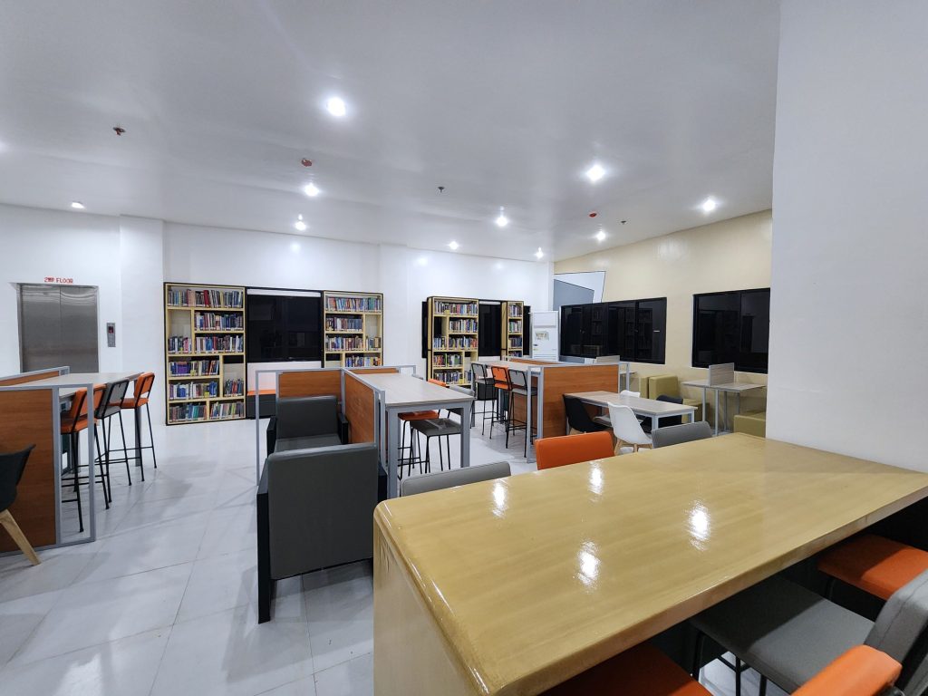 Warm reading area with a wood table beside the stacks