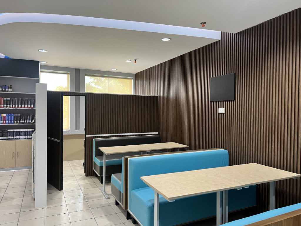 Teal upholstered study booths beside a window