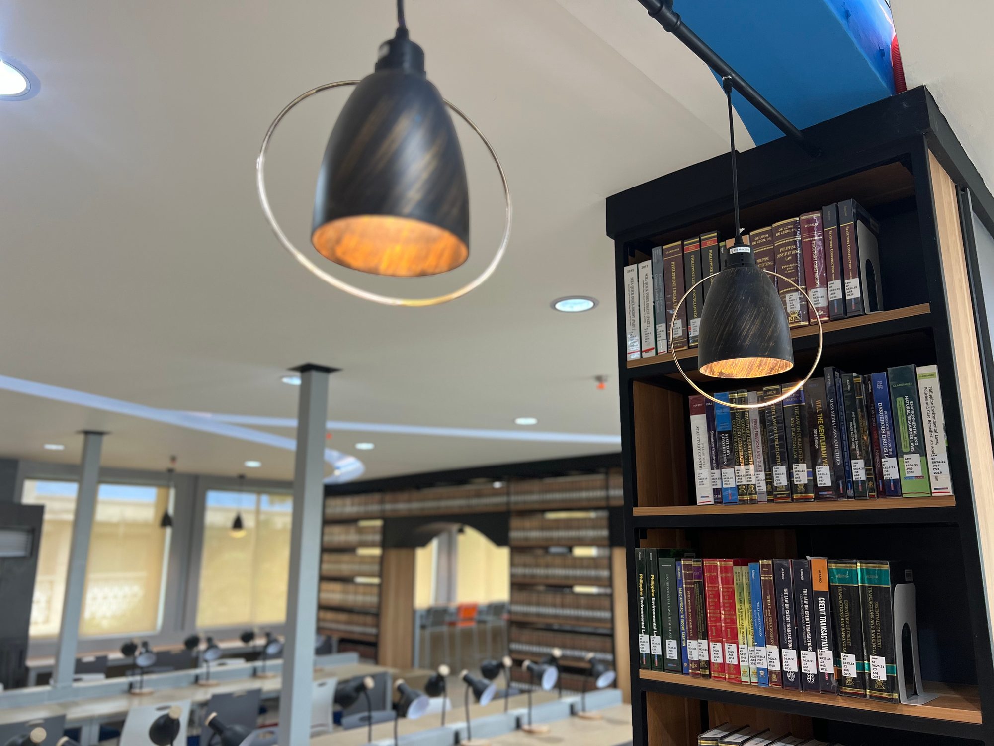 Pendant lighting over dark-wood library stacks