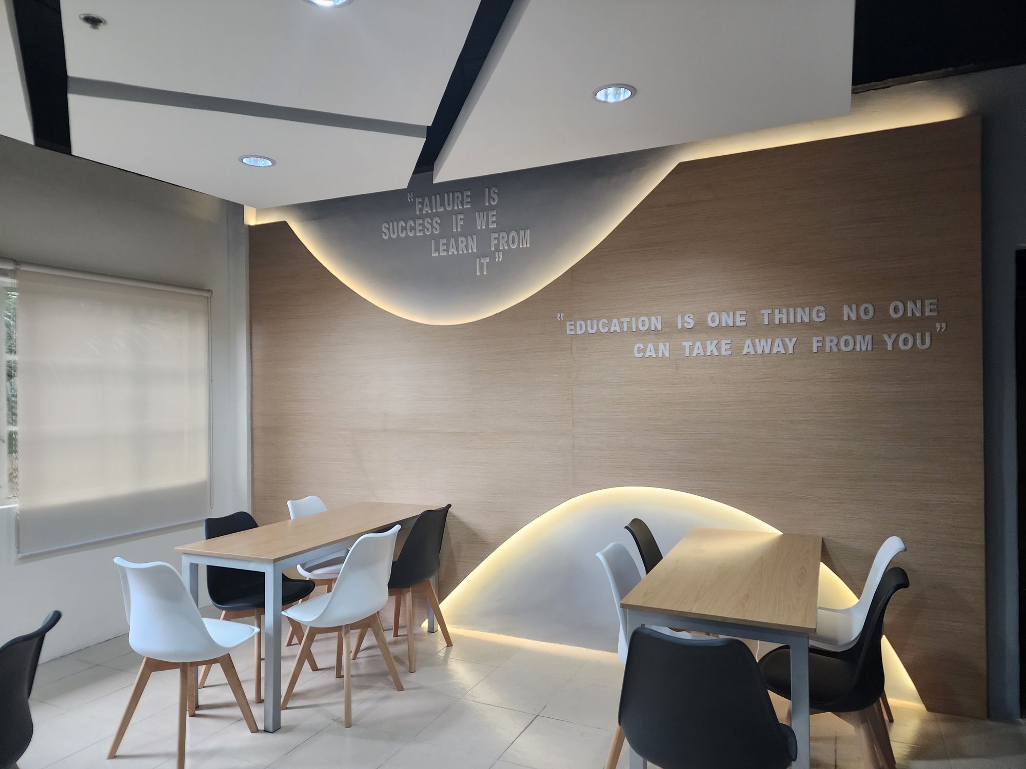Feature wall with a quote about education and curved cove lighting