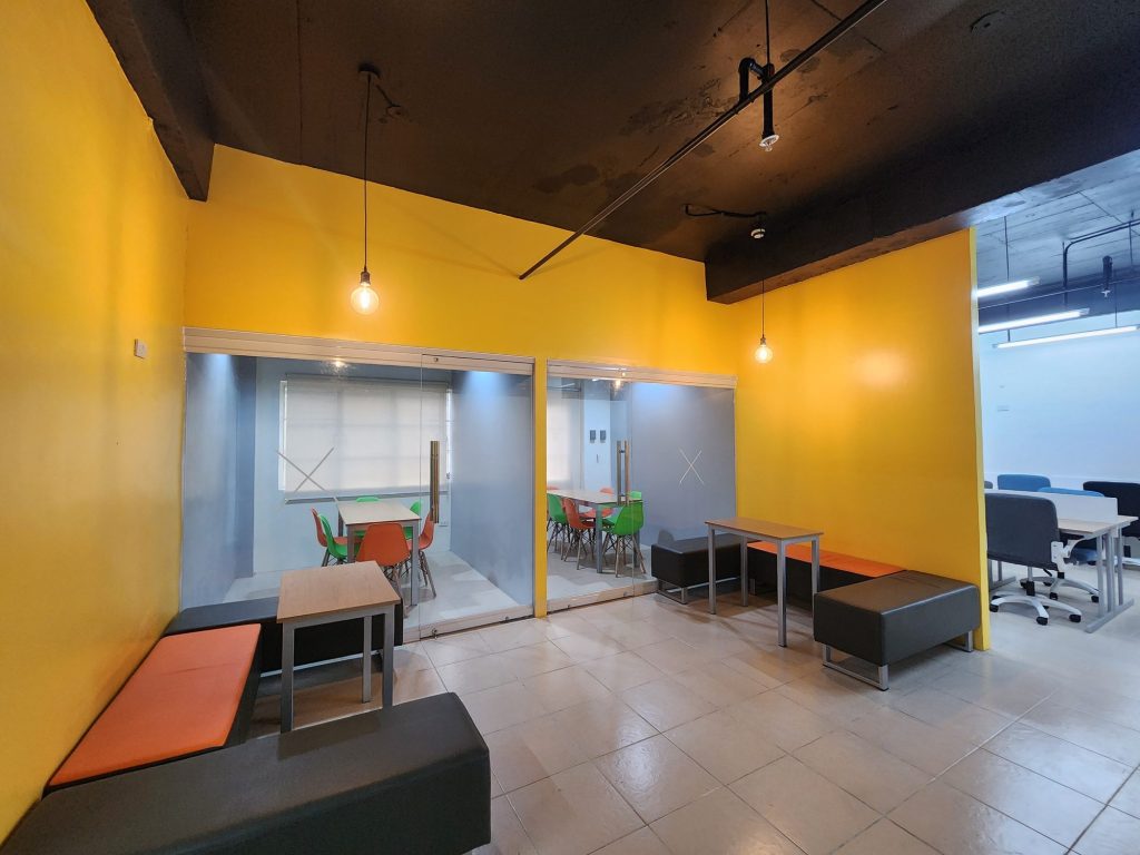 Bright yellow-walled glass group room with colorful seating