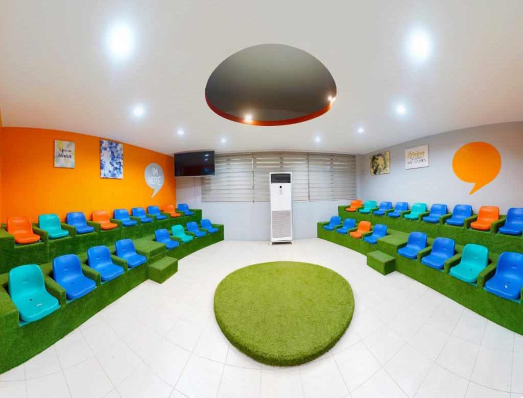 Stepped amphitheater seating with a round green rug for gatherings