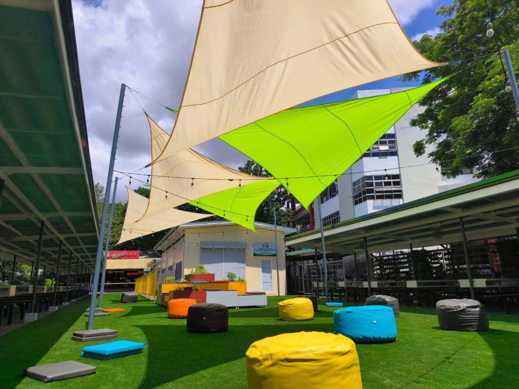 Open-air study deck with white sail shades over an astroturf lawn