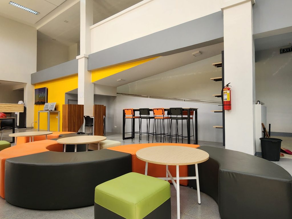 Curved orange and green bench seating with round tables
