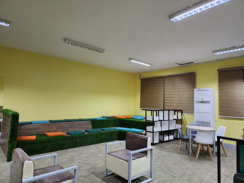 Warm yellow-walled lounge with soft seating and cube shelving
