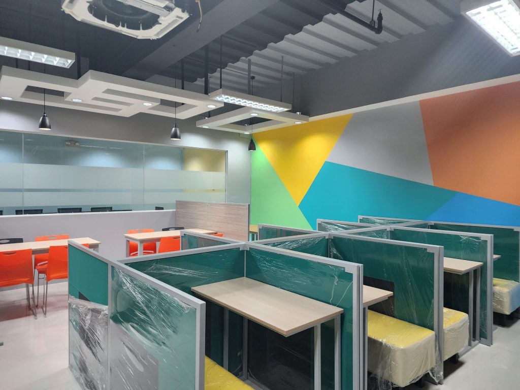 Study floor with a bold geometric color-blocked mural and teal booth seating
