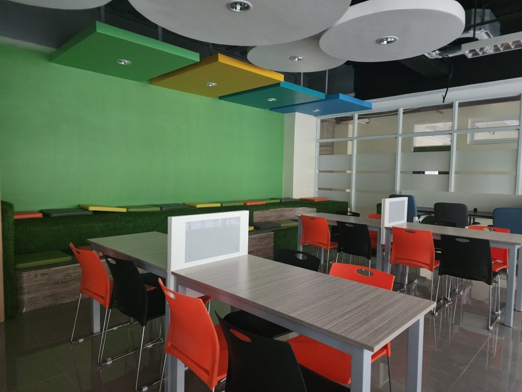 Green-walled study room with tables and red chairs