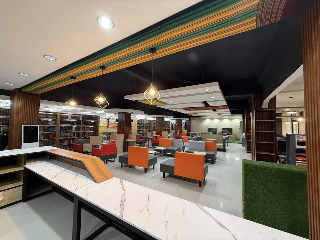 Reading room with a striped color ceiling feature, marble tables, and booth seating