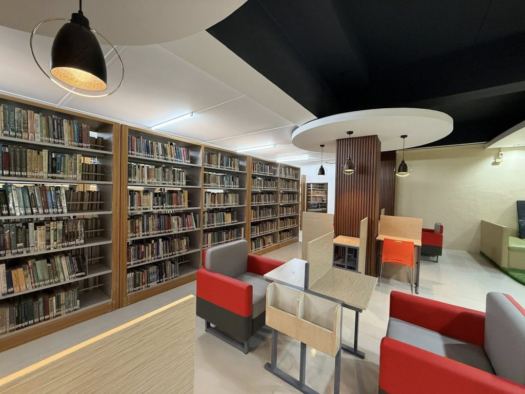 Tall library stacks with a pendant light and red reading chairs