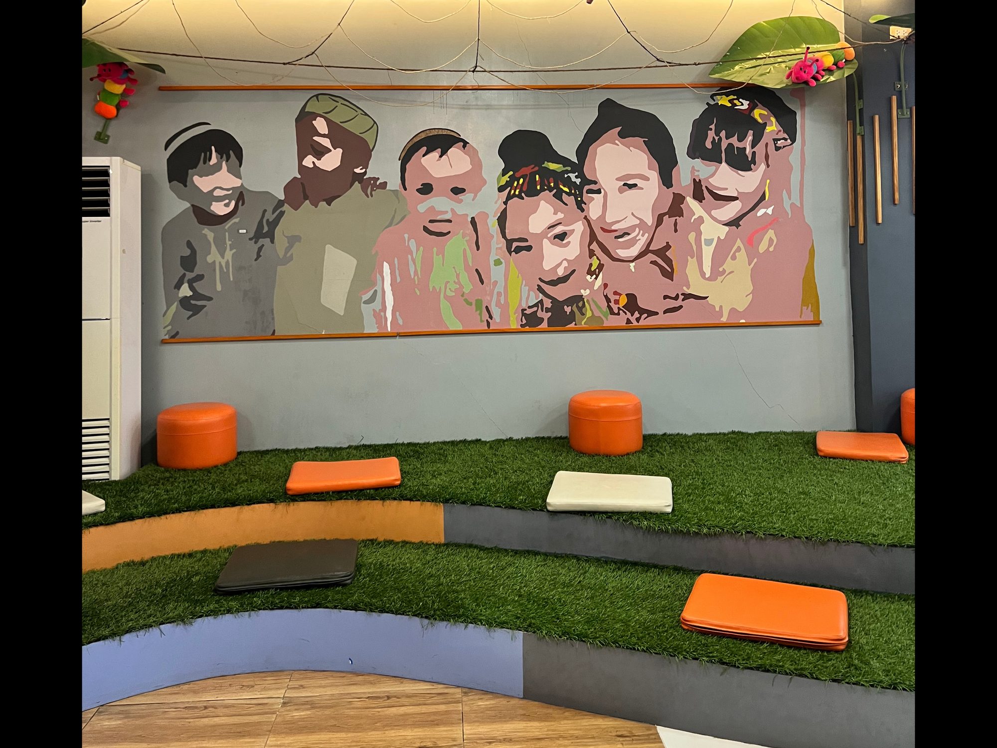 Community reading nook with a children's mural and cushioned astroturf steps
