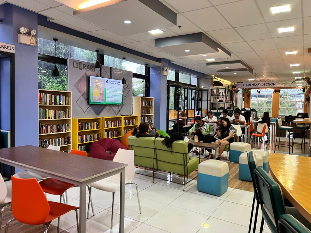 Students studying at tables among the stacks