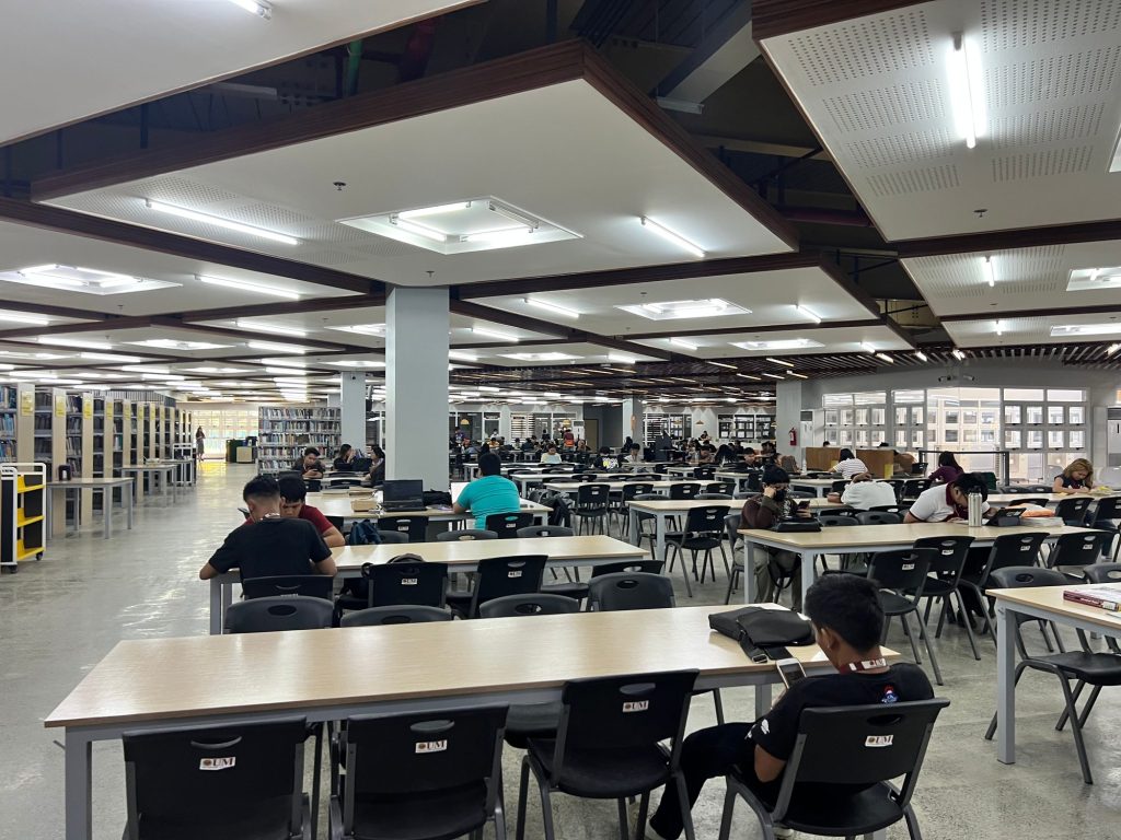 Wide reading hall with students working at long tables