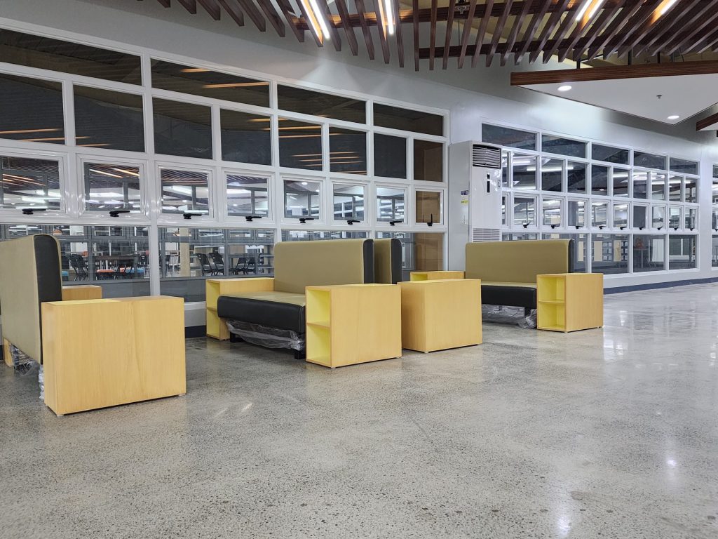 Wide open reading floor with yellow booth seating and glass-walled study rooms