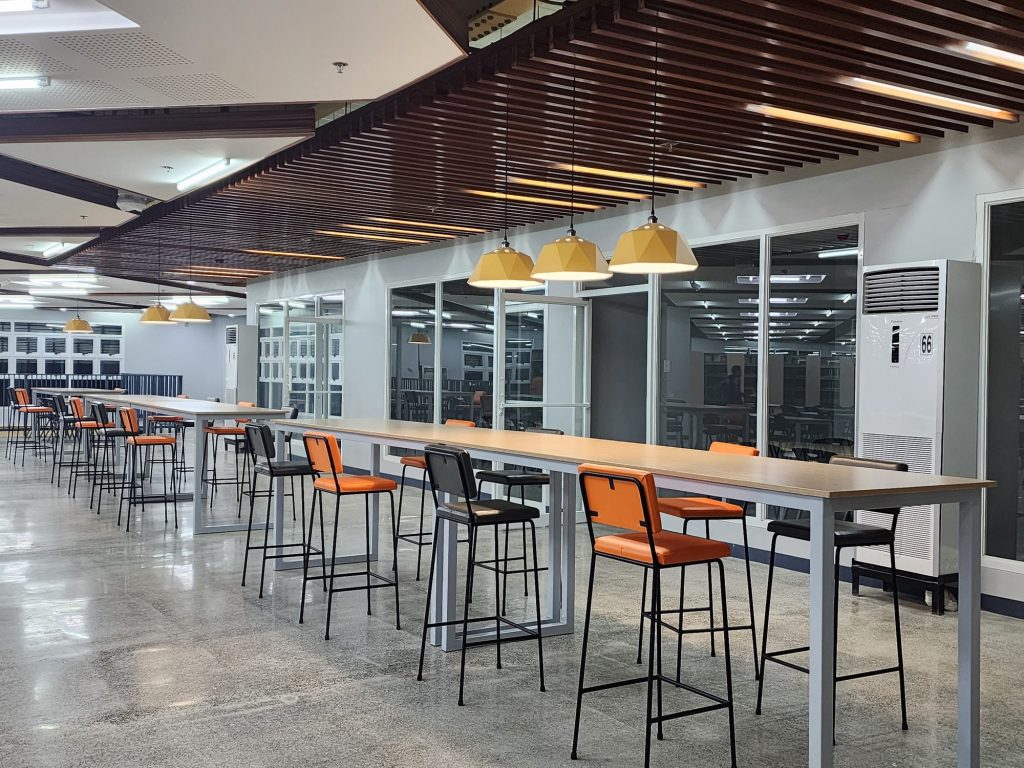Long study bars with orange stools beside glass study rooms